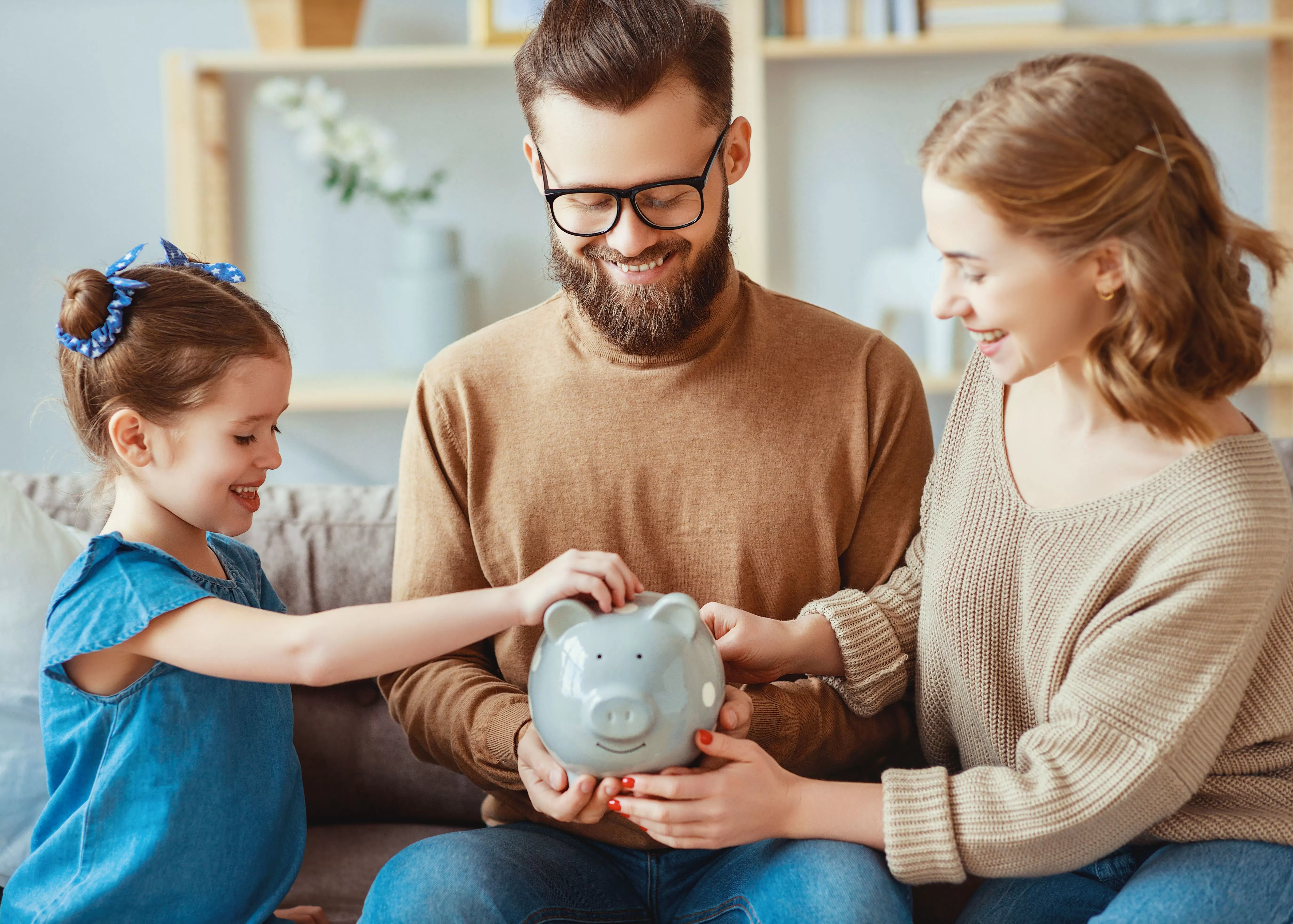 man and women with girl and piggy bank